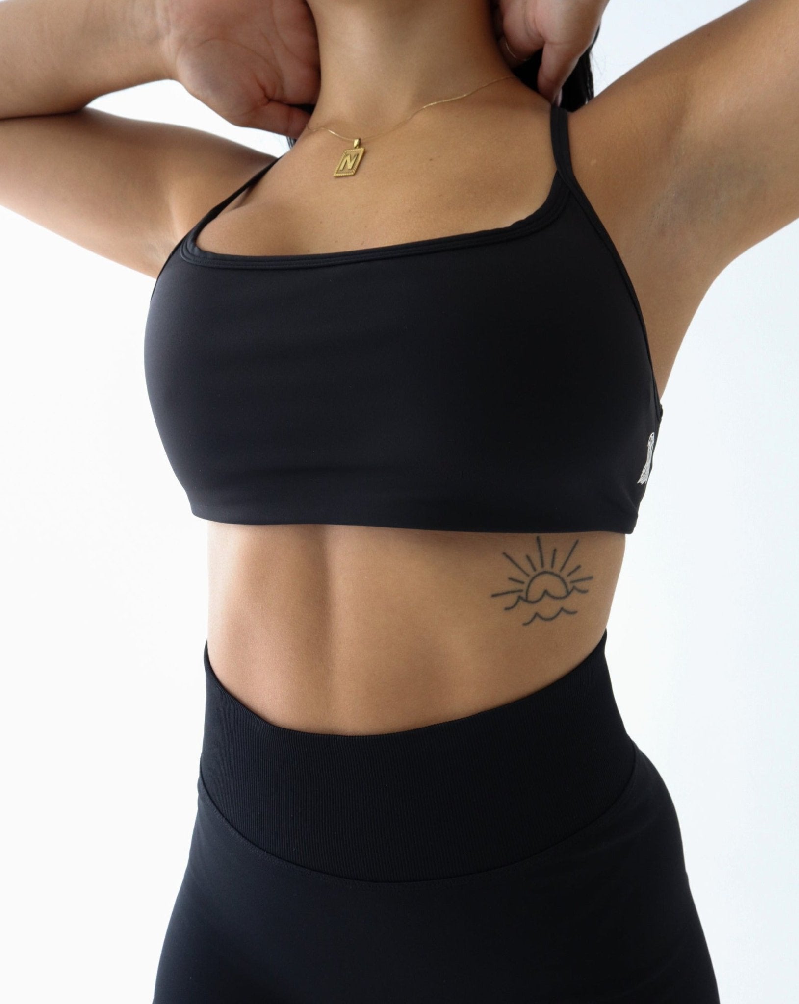 REFINE Sports Bra - BLACK - LIBERA Fitness Apparel. Revamp your gym wardrobe with our Refine Sports Bra, featuring double-layered, stretchy fabric for breathability and opacity. Elevate your style with the iconic LIBERA logo.